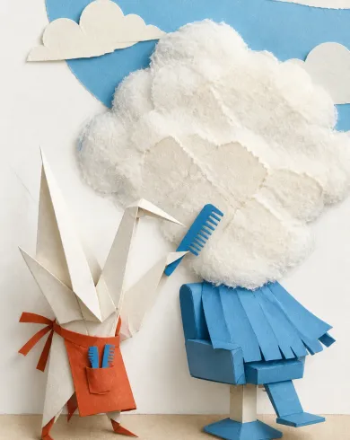 Handmade paper collage / dimensional assembly artwork showing a paper crane using blue-paper combs to tidy the fibrous edge of a white cloud. The vertical composition preserves a clear subject and tactile handmade detail.