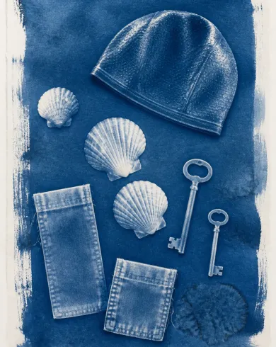 Sun-exposed cyanotype / cotton rag paper artwork depicting a swim cap, shells, keys and fabric pockets leaving cyanotype silhouettes of summer belongings. The vertical composition keeps the subject clear and preserves authentic craft texture.